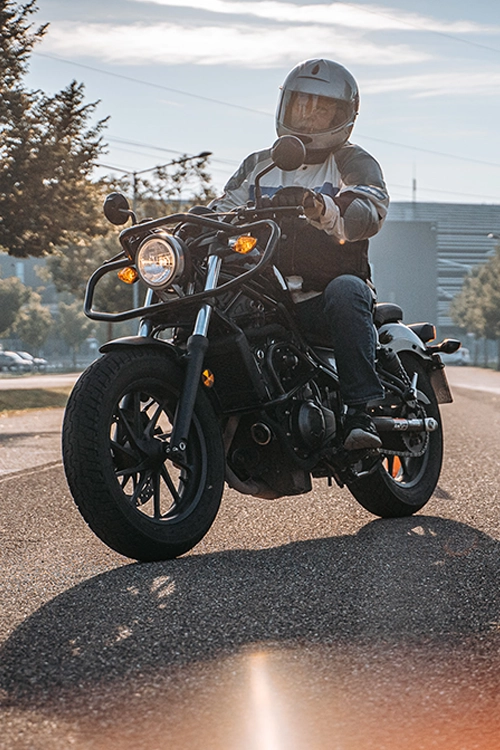 Motorradfahrer in voller Ausrüstung auf einer geraden Straße – sicherer Umgang mit Fahrzeugen in der Fahrschule.