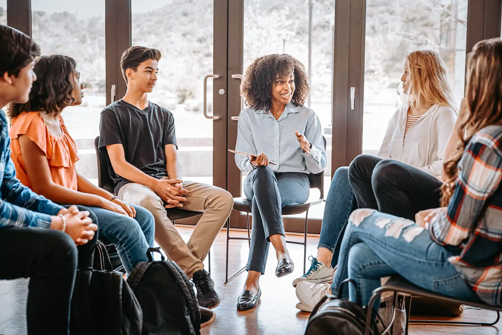 Gruppendiskussion zwischen jungen Fahrschülern und der Ausbilderin – Theorieunterricht für den sicheren Umgang mit Fahrzeugen.