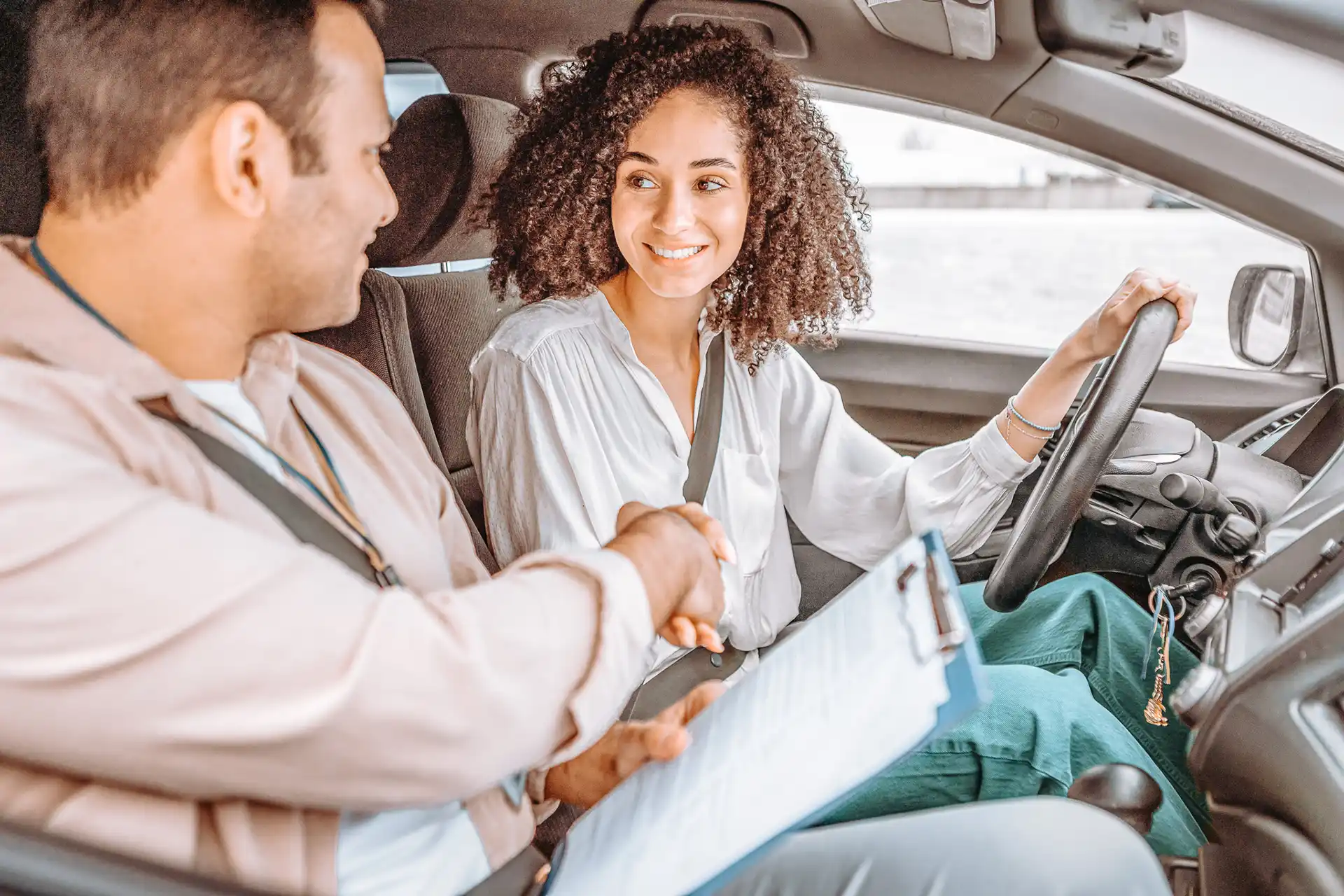 Fahrlehrer schüttelt Fahrschülerin die Hand nach erfolgreicher Fahrprüfung – Fahrschule für alle Arten von Fahrzeugen.